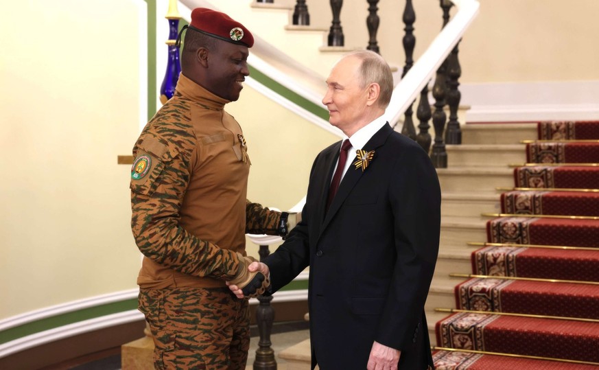 Le président russe Vladimir Poutine, à droite, serre la main du président du Burkina Faso Ibrahim Traore, à gauche, avant le défilé militaire du Jour de la Victoire, le 9 mai 2025.