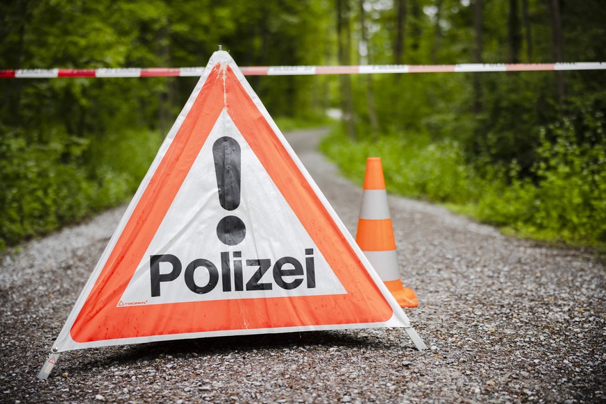 Ein gesperrter Waldweg mit einem Absperrband und einem Warndreieck mit der Aufschrift Polizei im Huerstwald, am Donnerstag, 5. Mai 2022 in Zuerich. Die Kantonspolizei Zuerich sperrte den Huerstwald im ...