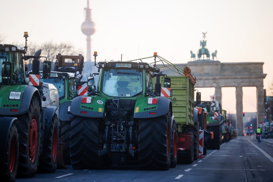 epa11065401 Tractors stand queued up in front of the Brandenburg Gate with the TV tower in the background during a nationwide farmers&#039; strike, in Berlin, Germany, 09 January 2024. Farmers went on ...