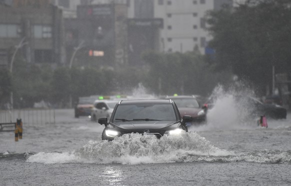 epa12249767 Vehicles drive through a flooded area in Haikou, Hainan Province, China, 20 July 2025. Typhoon Wipha, the sixth typhoon of the year, made landfall near Jiangmen City in south China&#039;s  ...