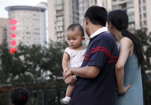 epa01807855 A couple with their toddler look at children playing in a park in Shanghai, China 27 July 2009. Authorities in Shanghai, China&amp;#039;s most economically developed city, are urging eligi ...