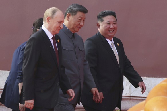In this photo provided by the North Korean government, Russian President Vladimir Putin, from left, Chinese President Xi Jinping and North Korean leader Kim Jong Un walk to attend a military parade ma ...