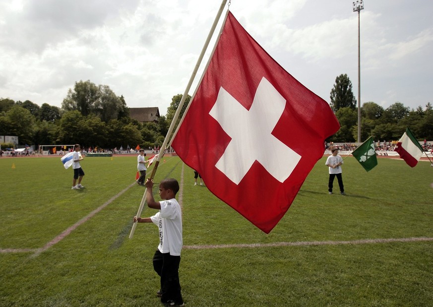 Ein kleiner farbiger Junge traegt stolz die Schweizer Fahne ins kleine Stadion des Jakob-Park zum Finale bei der Credit Suisse Schulfussballmeisterschaft in Basel am Mittwoch, 13. Juni 2007. In zwoelf ...