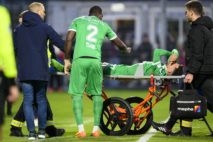 L&#039;entraineur yverdonnois Alessandro Mangiarratti, gauche, et le defenseur yverdonnois Mohamed Tijani, centre, soutiennent l&#039;attaquant yverdonnois Varol Tasar, droite, blesse sur une civiere  ...