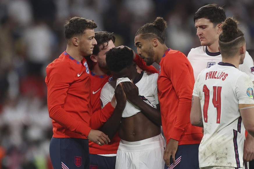 England players comfort teammate Bukayo Saka after he failed to score a penalty during a penalty shootout after extra time during of the Euro 2020 soccer championship final match between England and I ...