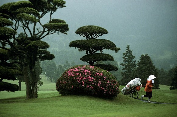 TOKYO, JAPAN - JUNE 1989: A Japanese woman caddy trudges through the mist. June 1989, at the Hachioji GMG golf course in Toyko, Japan. Women typically serve as caddies on Japanese golf courses. (Photo ...