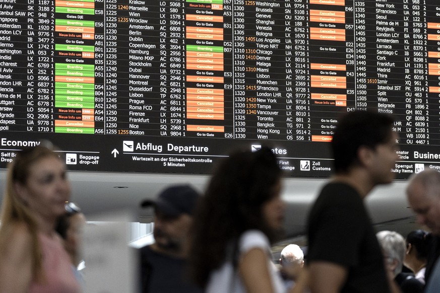epaselect epa11487356 Passengers look at screens informing on the flight situation at the Zurich Airport in Kloten, Switzerland, 19 July 2024. Due to a major worldwide IT outage, check-in for air trav ...