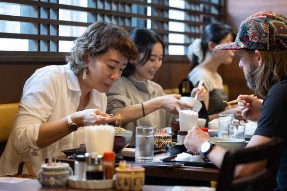 This photo taken on June 8, 2026 shows US tourist Wesley Smith (R) and his wife Maya Bourdeau eating lunch at the Natto Kobo Sendai-ya restaurant in Tokyo. The highly nutritious beans inoculated with  ...