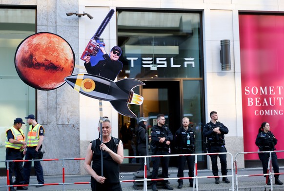 epa12065546 An activist from the New Generation holds a paper figure symbolizing Elon Musk on a rocket heading to Mars during a protest in front of a Tesla store in Berlin, Germany, 30 April 2025. Pro ...
