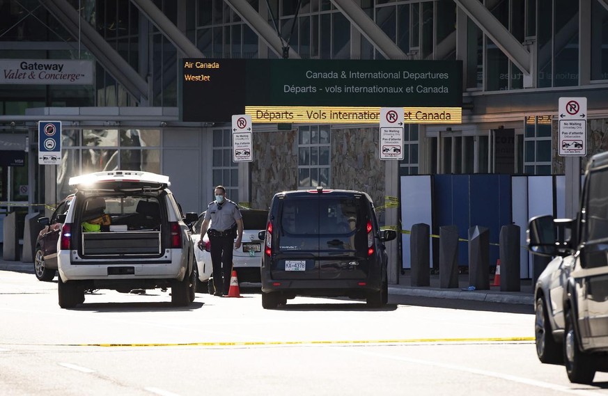 A Royal Canadian Mounted Police officer works at the scene as screens block off an area of the sidewalk after a shooting outside the international departures terminal at Vancouver International Airpor ...