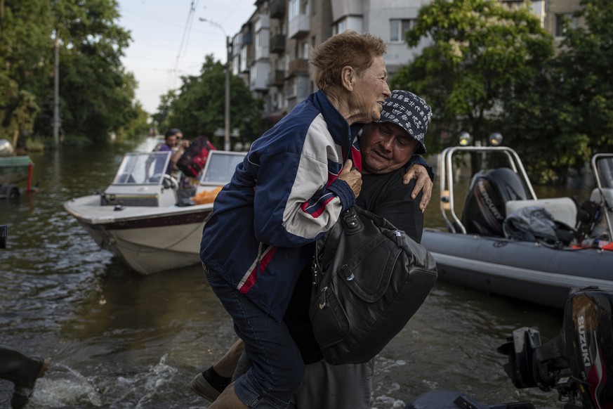 A volunteer carries a woman as she been evacuated from a flooded neighborhood of the left bank Dnipro river, in Kherson, Ukraine, Friday, June 9, 2023. In Ukraine, the governor of the Kherson region,  ...