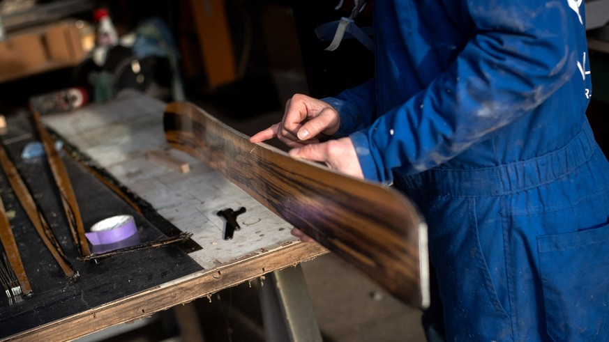 Head of the Villacampa Pyrenées workshop and brand development Eric Antier shows a trainee how to sand the edge of a wooden ski after cutting away the excess fabric and resin at the company&#039;s wor ...