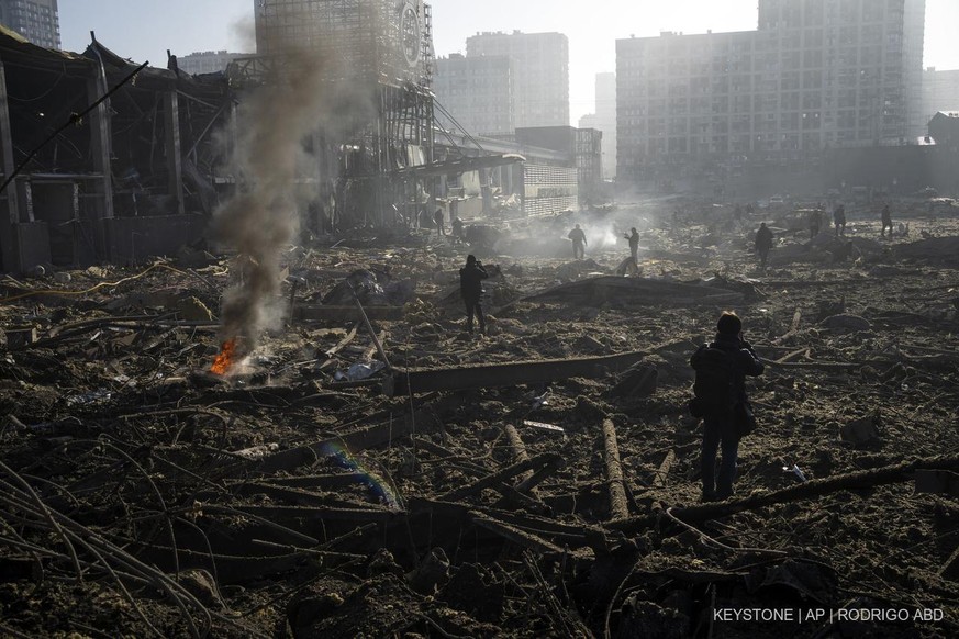 People gather amid the destruction caused after shelling of a shopping center, in Kyiv, Ukraine, Monday, March 21, 2022. (AP Photo/ (AP Photo/Rodrigo Abd)