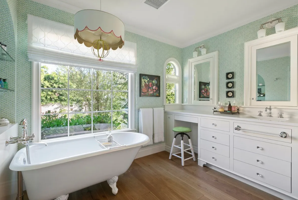 L'une des salles de bains de la maison, qui fait «écho à l'énergie du salon» avec un papier peint vert clair, une étagère intégrée «cintrée» et une «baignoire sur pattes».