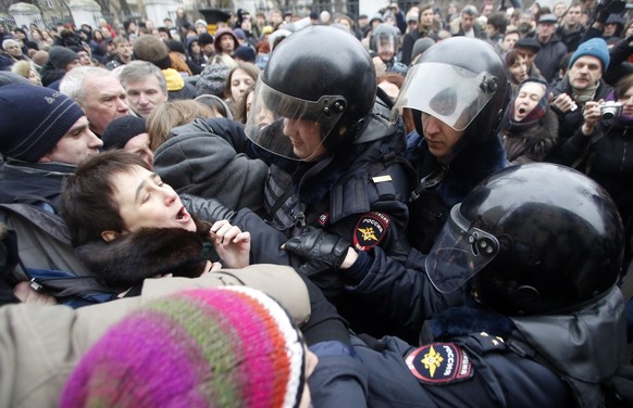 Russian police officers detain opposition activists outside a court room in Moscow, Russia, Monday, Feb. 24, 2014, where hearings started against opposition activists detained on May 6, 2012 during a  ...