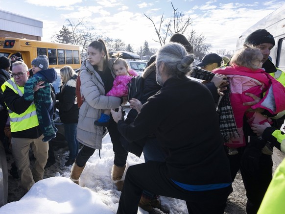 Parents and their children are loaded onto a warming bus as they wait for news after a bus crashed into a daycare centre in Laval, Quebec, on Wednesday, Feb. 8, 2023. (Ryan Remiorz/The Canadian Press  ...