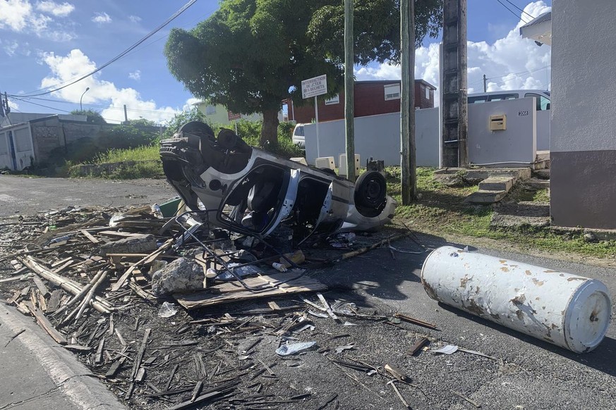 An overturned car is pictured in a s street of Le Gosier, Guadeloupe island, Sunday, Nov.21, 2021. French authorities are sending police special forces to the Caribbean island of Guadeloupe, an overse ...