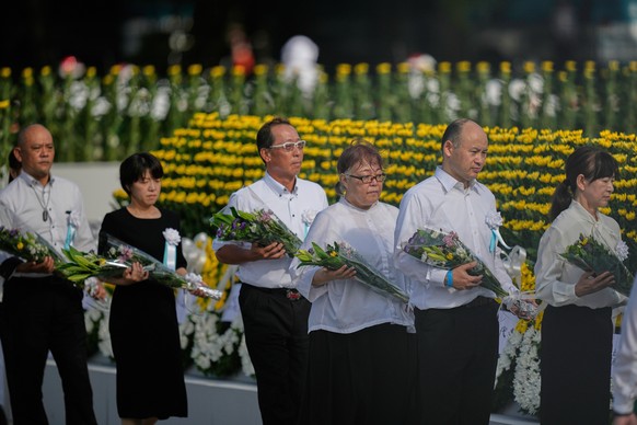 Visitors offer flowers to Hiroshima Memorial Cenotaph during the ceremony to mark the 80th anniversary of the bombing at the Hiroshima Peace Memorial Park in Hiroshima, western Japan, Wednesday, Aug.  ...