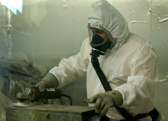Ein Arbeiter mit Atemschutz und Schutzanzug befreit Rohre und Leitungen von Asbestrueckstaenden, aufgenommen am Dienstag, 25. Februar 2003, im Werd Hochhaus in Zuerich. Das Werd Hochhaus wird zurzeit  ...