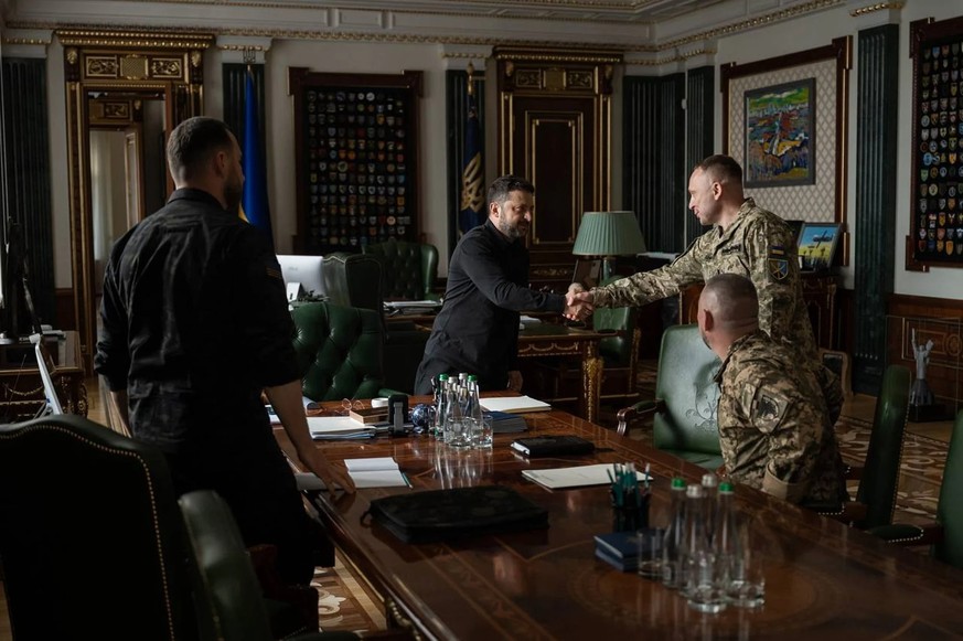 Le président ukrainien Volodymyr Zelensky (au centre) félicite son nouveau Commandant en chef des forces armées, Mykhaïlo Drapatiy.