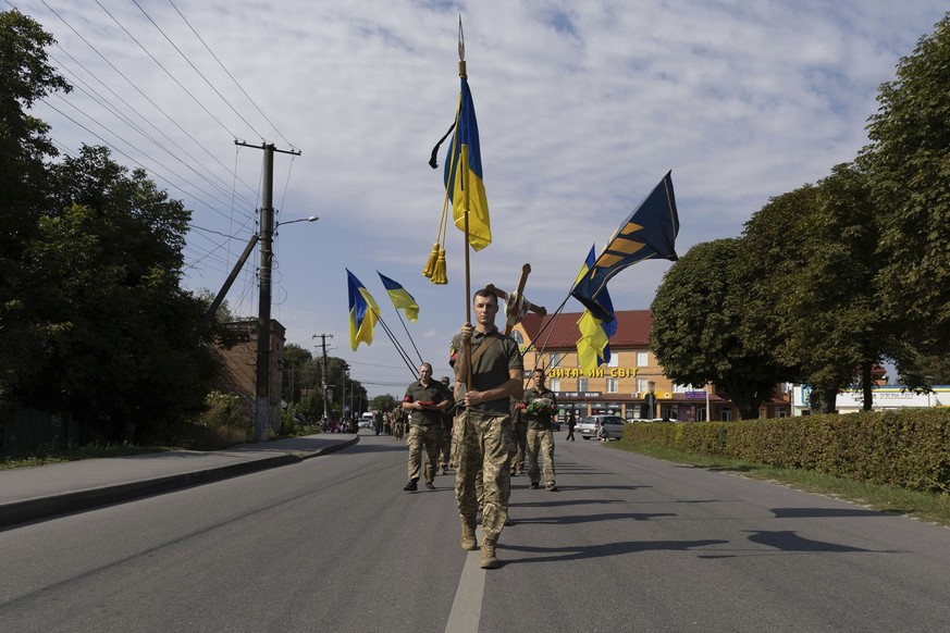 Ukrainian servicemen carry National flags and a cross during the funeral ceremony of killed Ukrainian soldier Vadym Belov, of 3rd Assault brigade, in Polonne, Khmelnytskyi region, Ukraine, Wednesday,  ...