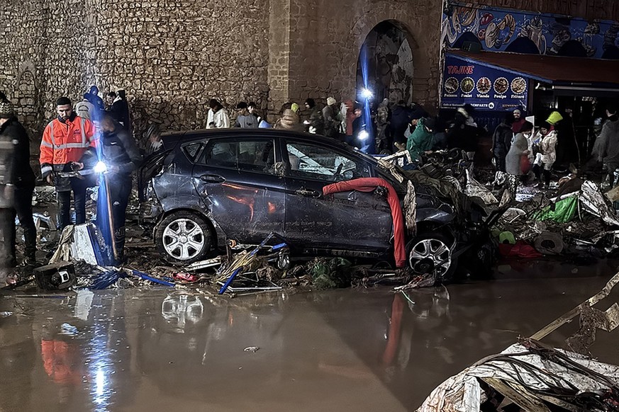 People walk past debris left by a flash flood in Safi on December 14, 2025. Flash-flooding caused by sudden, heavy rain killed at least 21 people in the Moroccan coastal town of Safi on December 14, l ...