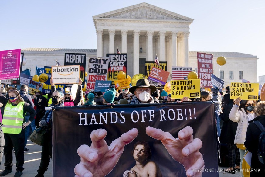 Stephen Parlato of Boulder, Colo., holds a sign that reads &quot;Hands Off Roe!!!&quot; as abortion rights advocates and anti-abortion protesters demonstrate in front of the U.S. Supreme Court, Wednes ...