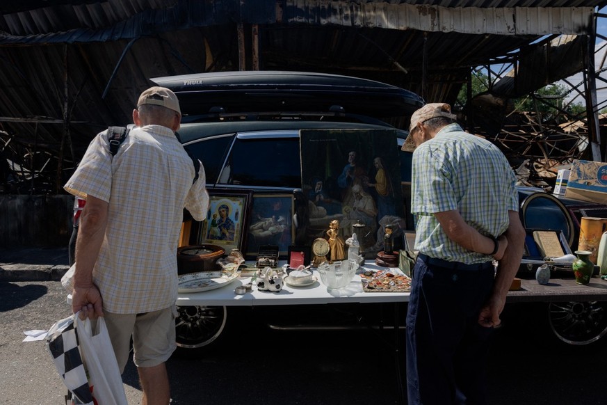(FILES) People look at the goods at a vendor's stall at a damaged street market following strikes in Petrivka, one of Kyiv's neighborhoods on August 9, 2026, amid the Russian invasion of Ukr ...