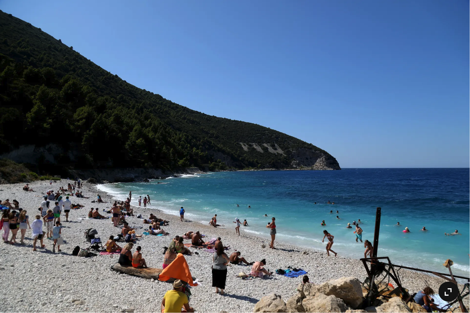 Des touristes prennent le soleil près des vestiges d’un bunker datant de la guerre froide, sur une plage de l’île de Sazan.