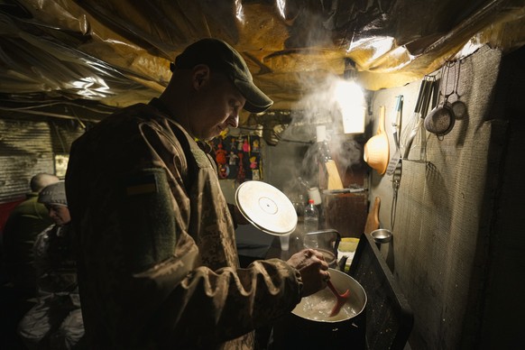 A Ukrainian serviceman cooks in a bunker on a frontline position outside Avdiivka, Donetsk region, eastern Ukraine, Friday, Feb. 4, 2022. Washington is raising the rhetoric about the buildup of Russia ...