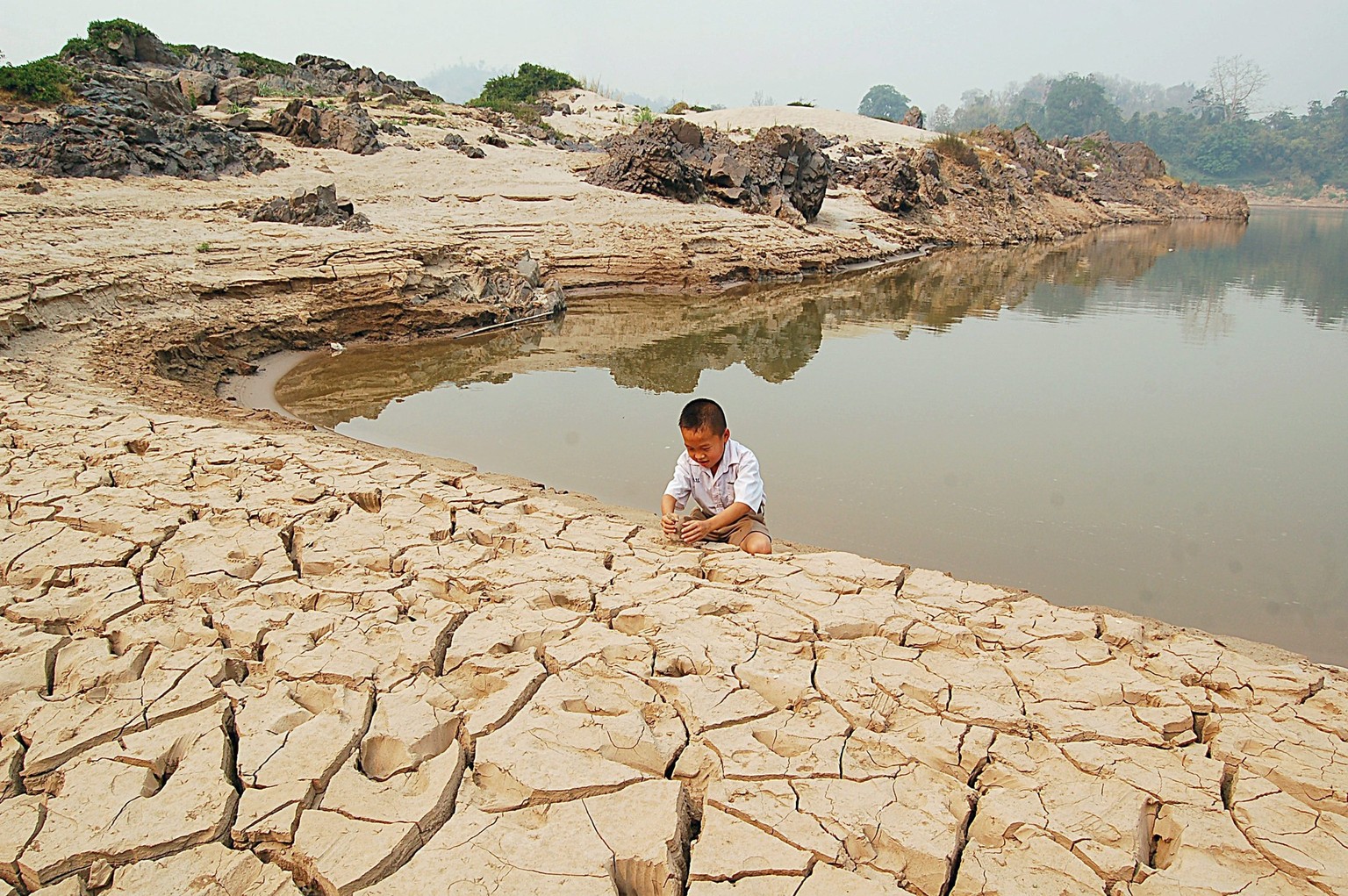 epa02072749 A photo made available on 10 March 2010 shows a Thai schoolboy play on a dried up reservoir of the Mekong River following a drought affecting the Thai-Lao border city of Wiang Kaen, Chiang ...
