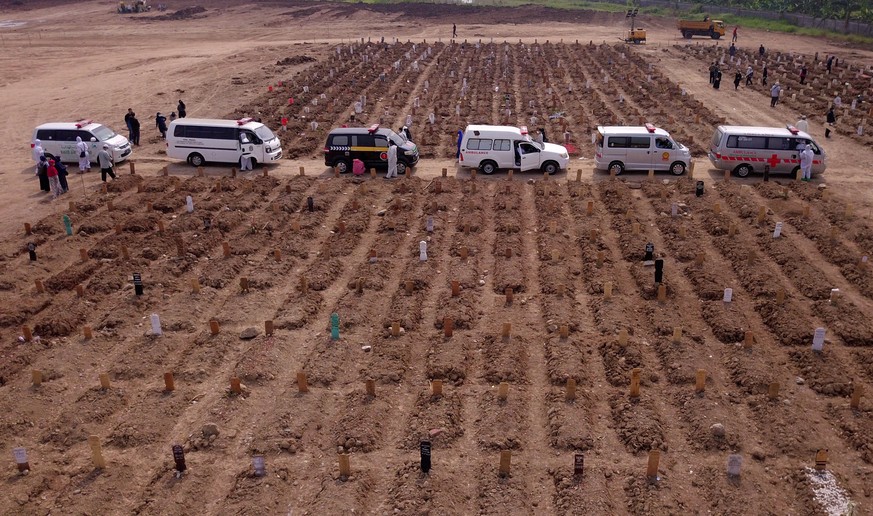 epa09327796 An aerial photo taken with a drone shows ambulances queue for funeral at a cemetery dedicated for COVID-19 victims in Jakarta, Indonesia, 07 July 2021. Indonesia has recorded over 2,200,00 ...