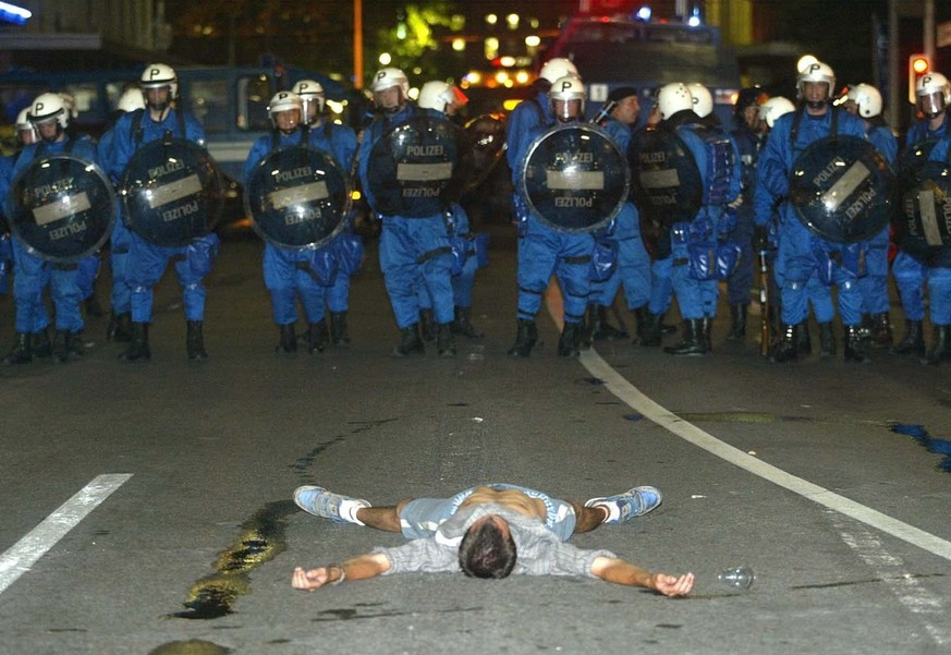 A protester stretches out on a street in Geneva in front of a a cordon of anti-riot police who are blocking the way for demonstraters in Geneva, late Monday 02 June 2003. Police blocked about 100 demo ...