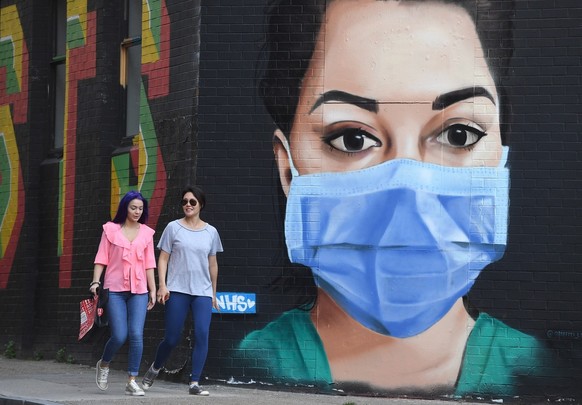 epa08377979 Pedistrians walk past an artwork depicting a nurse in wearing a face mask in east London, Britain, 22 April 2020. British Prime Minister Johnson has announced that Britons can only leave t ...