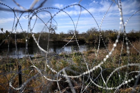 The Rio Grande river, that marks the US-Mexico border, is pictured through razor wire at Shelby Park in Eagle Pass, Texas, on February 18, 2026. (Photo by RONALDO SCHEMIDT / AFP)