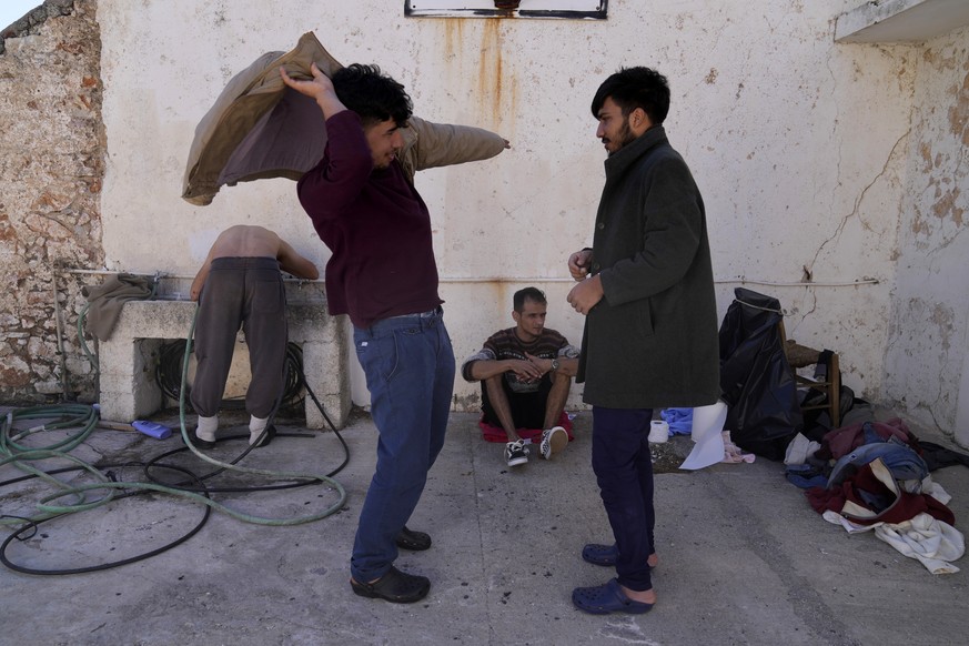 Migrants, most of them from Afghanistan, gather at an old school used as a temporary shelter on the island of Kythira, southern Greece, Thursday, Oct. 6, 2022. Bodies floated amid splintered wreckage  ...