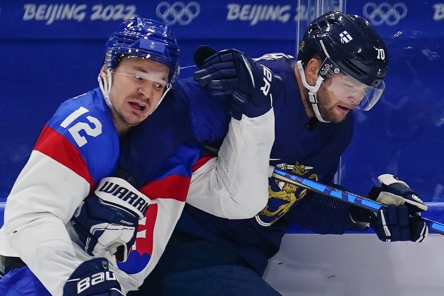 Slovakia&#039;s Milos Kelemen (12) and Finland&#039;s Teemu Hartikainen (70) get tangled as they chase the puck along the boards during a men&#039;s semifinal hockey game at the 2022 Winter Olympics,  ...