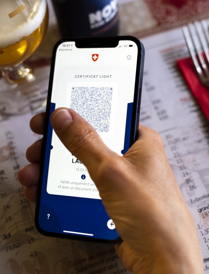 Une personne tient dans sa main un smartphone avec l&#039;application Certifact Covid suisse et un certificat light dans un restaurant ce vendredi 10 septembre 2021 a Rances dans le canton de Vaud. De ...