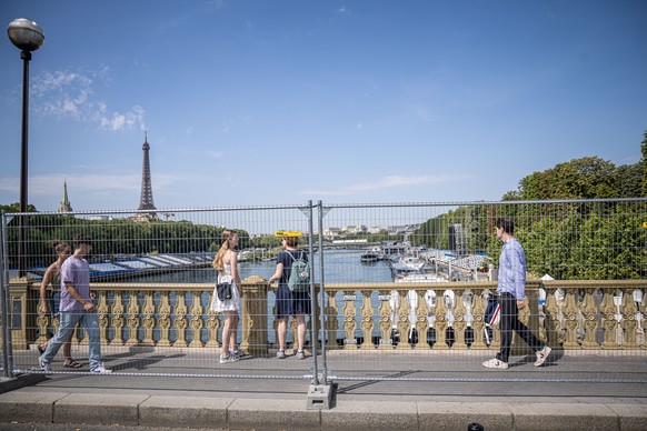 epa11487680 Tourists stroll behind security fences delimiting the forbidden perimeter reserved for the opening ceremony of the Paris 2024 Olympic Games along the Seine river in Paris, France, 19 July  ...