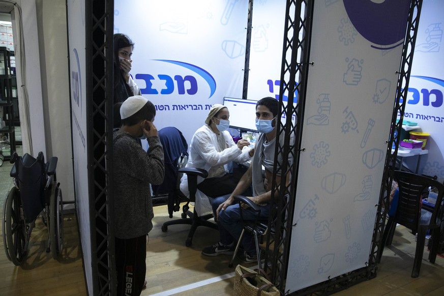 An Israeli man receives a Pfizer-BioNTech COVID-19 vaccine during an event to encourage the vaccination of young Israelis at a vaccination center in the Israeli city of Holon near Tel Aviv, Monday, Fe ...