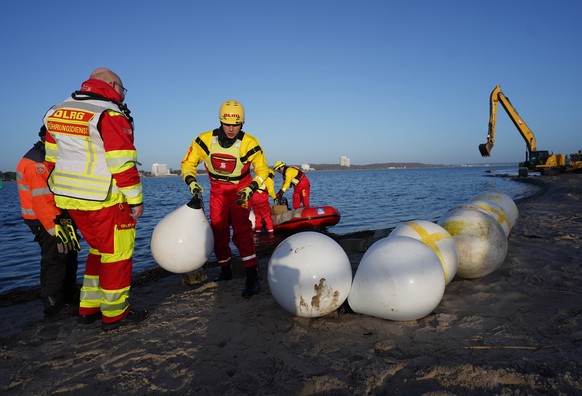 27.03.2026, Schleswig-Holstein, Timmendorfer Strand: Helfer tragen Bojen an den Strand an der Ostsee. Der in der Ostsee vor Niendorf gestrandete Wahl hat sich offenbar befreit. Das Tier war am fr�hen  ...