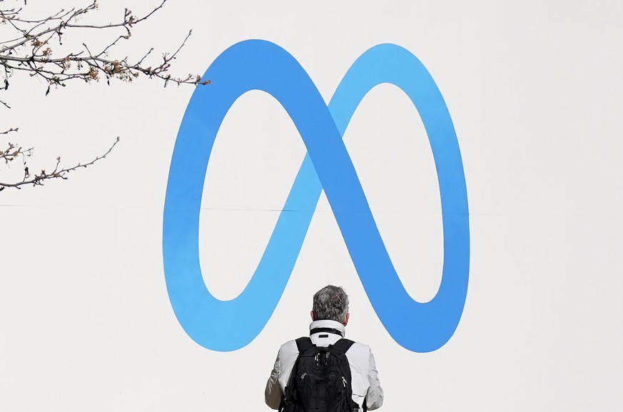 A person stands in front of a Meta sign outside of the company&#039;s headquarters in Menlo Park, Calif., Tuesday, March 7, 2023. Facebook?s parent Meta will slash another 10,000 jobs and will not fil ...