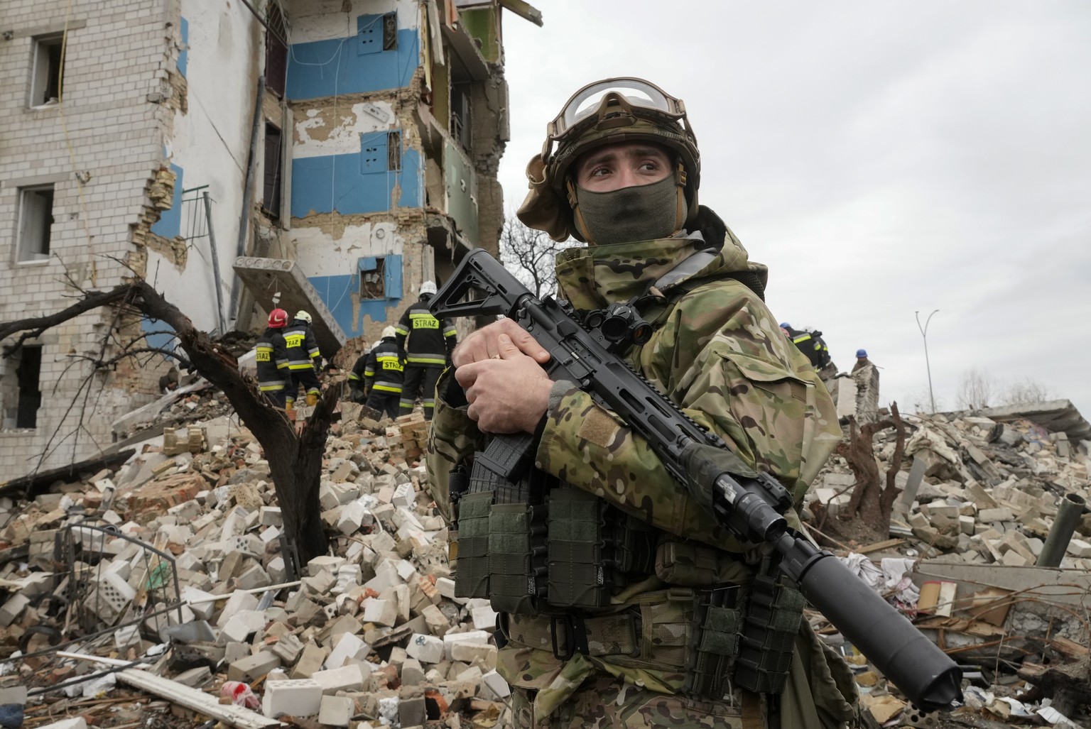 A Ukrainian soldier stands against the background of an apartment house ruined in the Russian shelling in Borodyanka, Ukraine, Wednesday, Apr. 6, 2022. (AP Photo/Efrem Lukatsky)