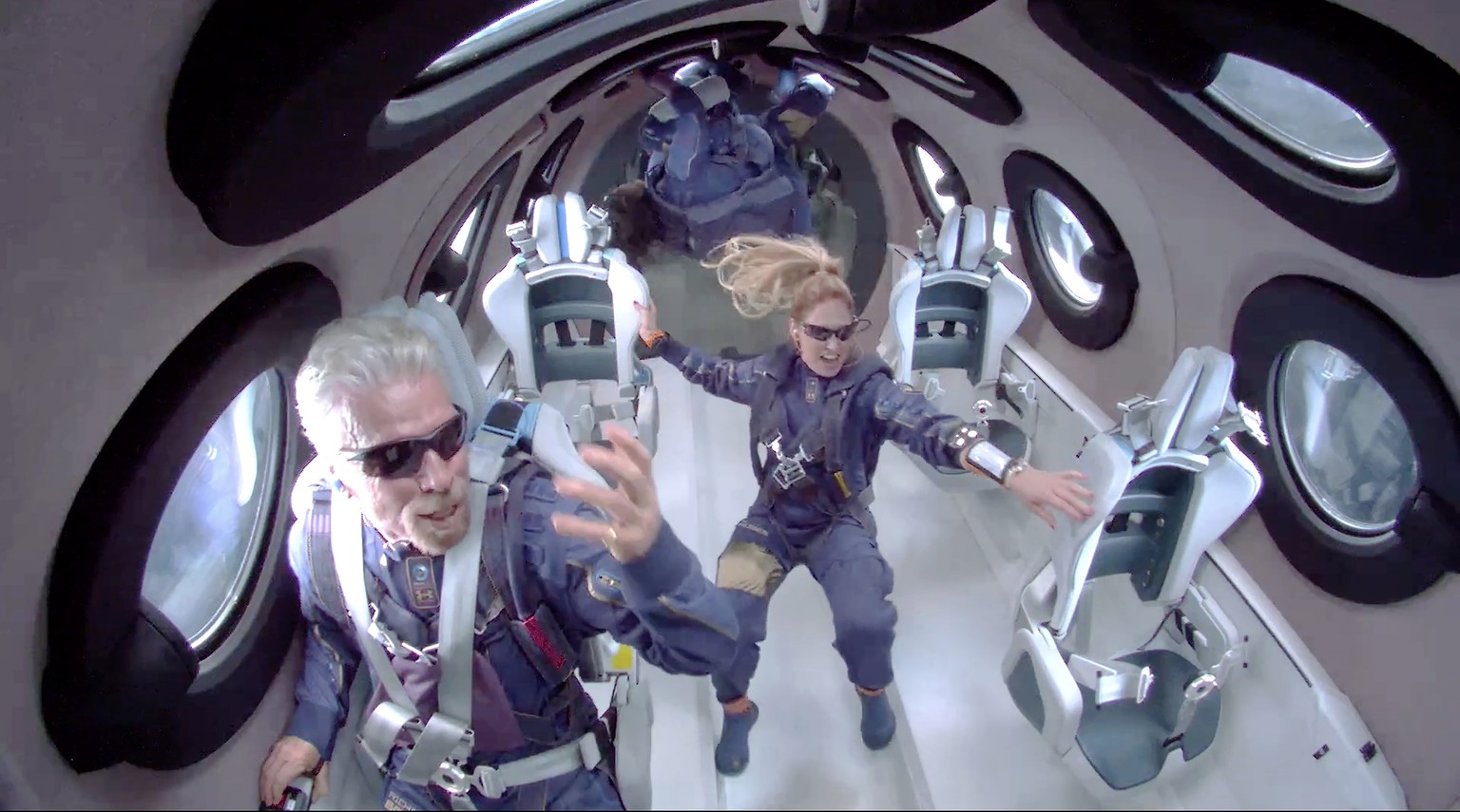 epa09339453 A framegrab from a video made available by Virgin Galatic shows Sir Richard Branson (L) aboard SpaceShip Two Unity 22 as they attain zero gravity during their flight after take off from Sp ...