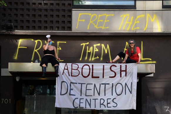 epa09669085 Protesters are seen outside of the Park hotel quarantine facility where it is believed Serbian tennis player Novak Djokovic is being detained in Melbourne, Australia, 06 January 2022. Worl ...
