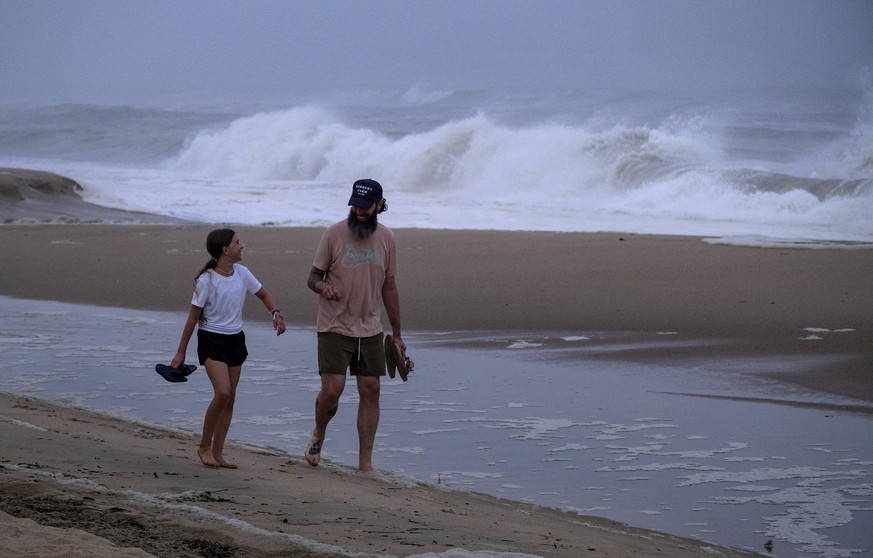 Ryan Madigan, and his daughter Charolette Madigan, 11, of Cold Spring Harbor, N.Y., stand along a beach in Montauk, N.Y., Saturday, Aug. 21, 2021, as Hurricane Henri churns up waves as the storm appro ...