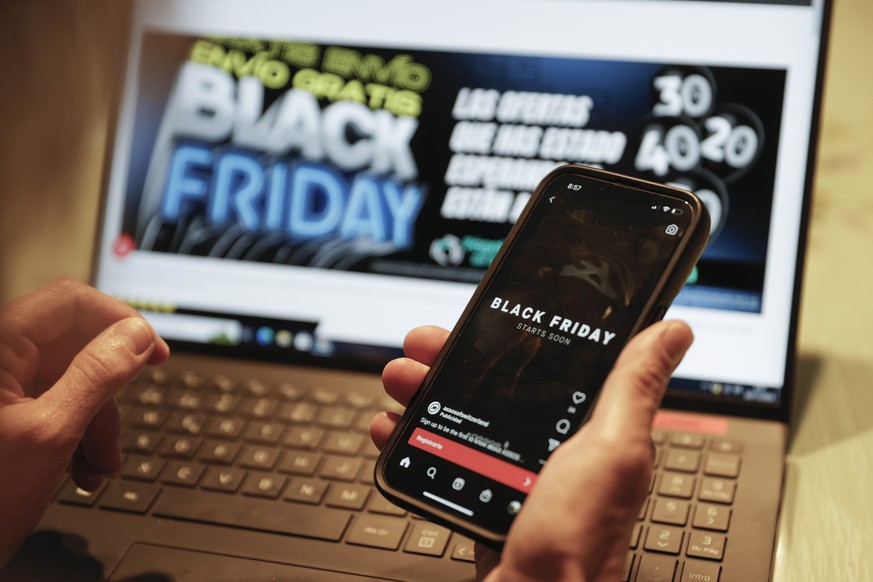 Un consommateur consulte les offres du Black Friday sur son ordinateur et son smartphone.