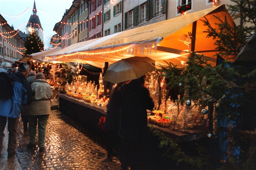 Marktgaenger betrachten einen weihnaechtlich geschmueckten Verkaufsstand am Weihnachtsmarkt in Bremgarten/AG am 6. Dezember 2002. (KEYSTONE/Gaetan Bally) : FILM]