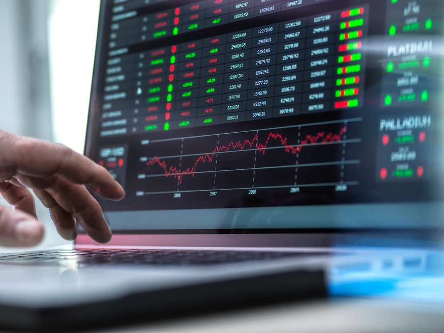Un trader devant son ordinateur portable avec graphiques boursiers.