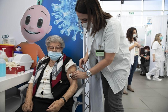 An Israeli woman receives a COVID-19 vaccine at a temporary vaccination center in the lobby of a gymnasium in Tel Aviv, Israel, Monday, Dec. 21, 2020. (AP Photo/Sebastian Scheiner)